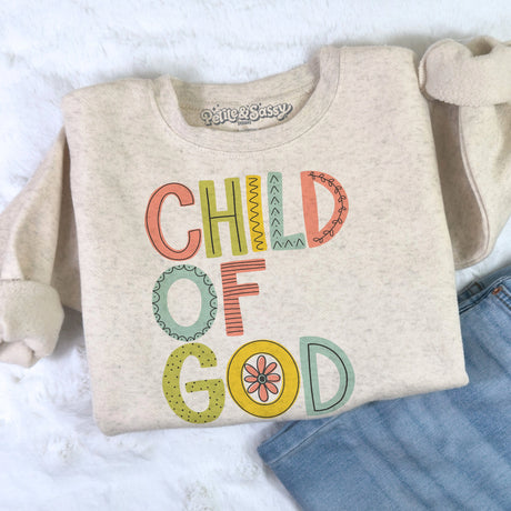 Folded sweatshirt with 'Child of God' text on a light background