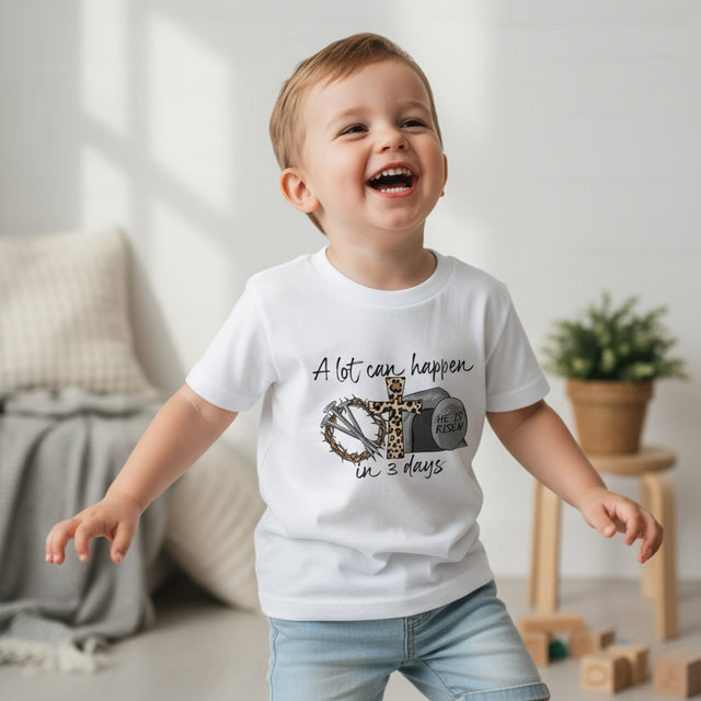 Child wearing a white t-shirt with a graphic design and text, standing in a room with a neutral background.