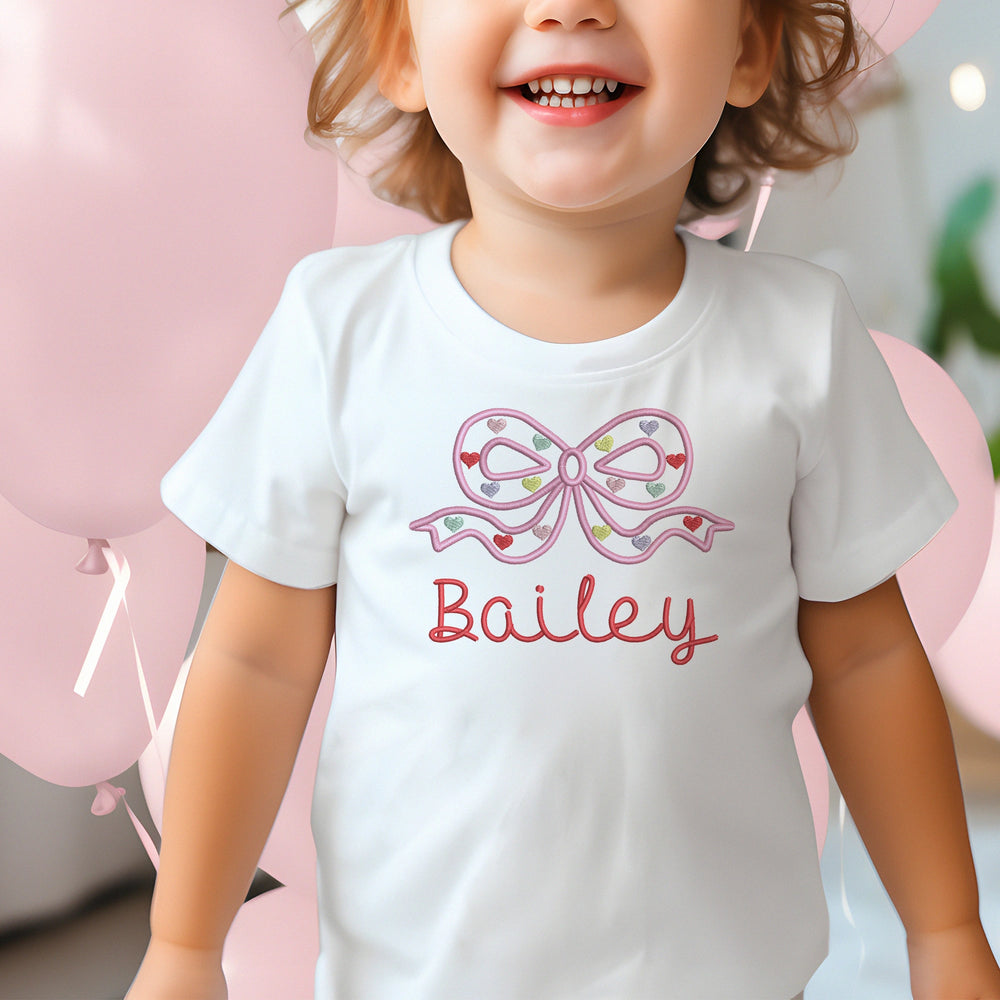 White baby romper with pink bow and 'Georgia' text on a red and white striped background