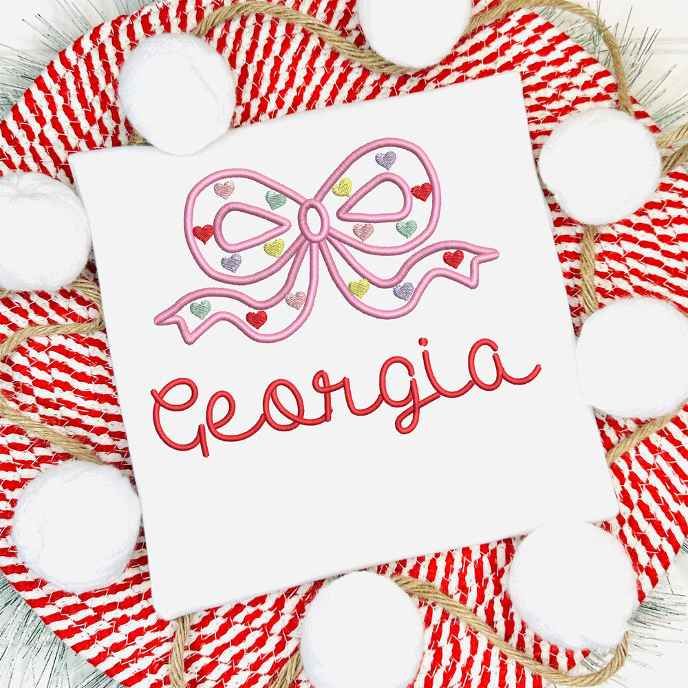 White baby romper with pink bow and 'Georgia' text on a red and white striped background