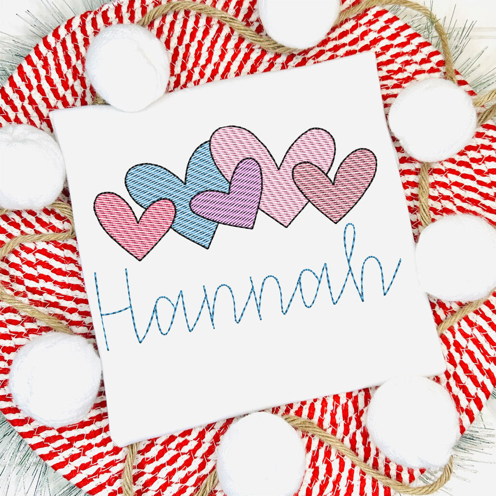 White pillow with embroidered hearts and name 'Hannah' on a red and white striped background