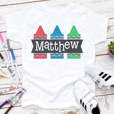 Back to school shirt featuring a trio of colorful crayons in red, blue and green. Personalized this soft t-shirt with your chils name.